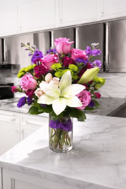 Mother’s Day bouquet with pink roses, white lily, and colorful flowers in a glass vase on a marble table